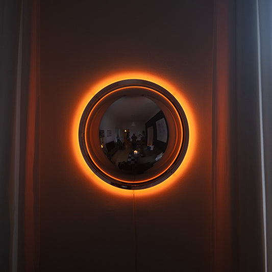 Lieve ronde spiegel wandlamp met warme halo-gloed aan donkere wand